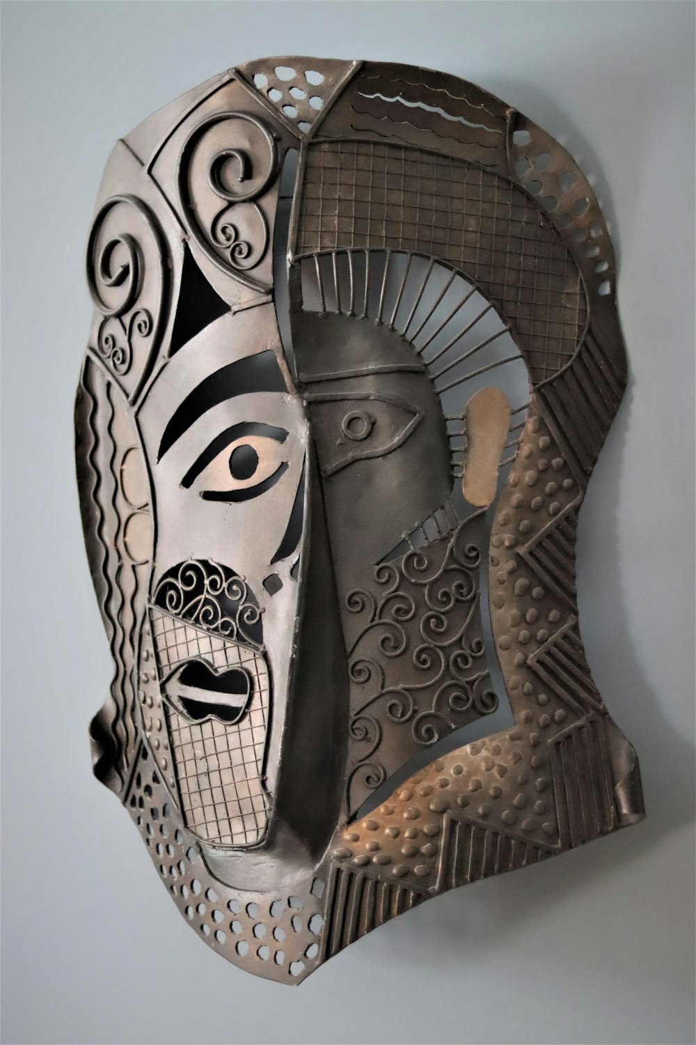 a metal mask hanging on a wall