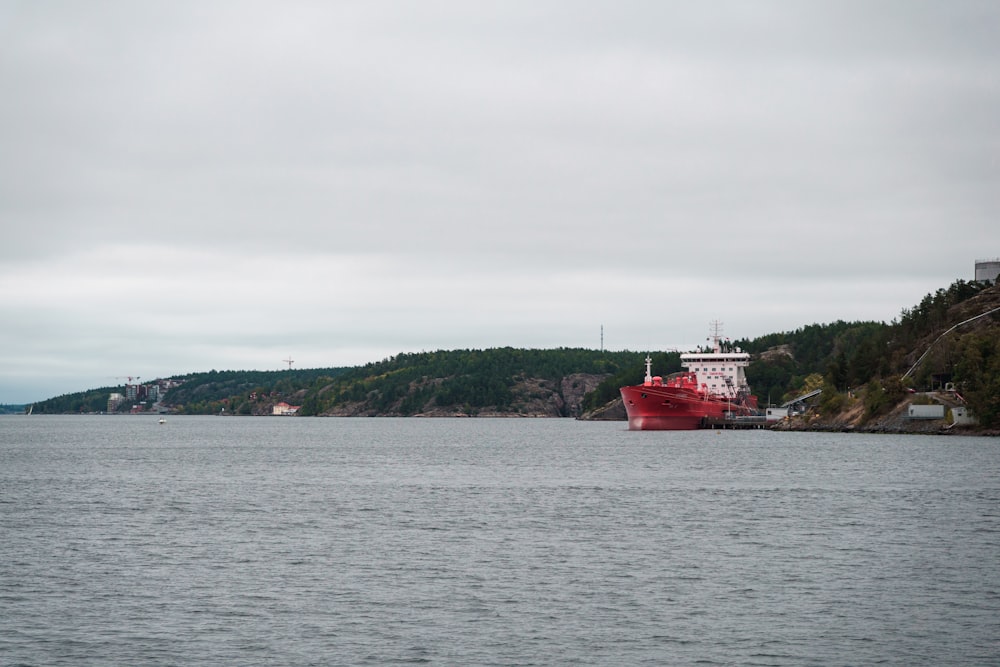 a large red boat floating on top of a large body of water