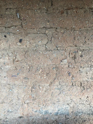 Close-up of a natural soil pavement being compacted with eco-friendly materials under sunlight.