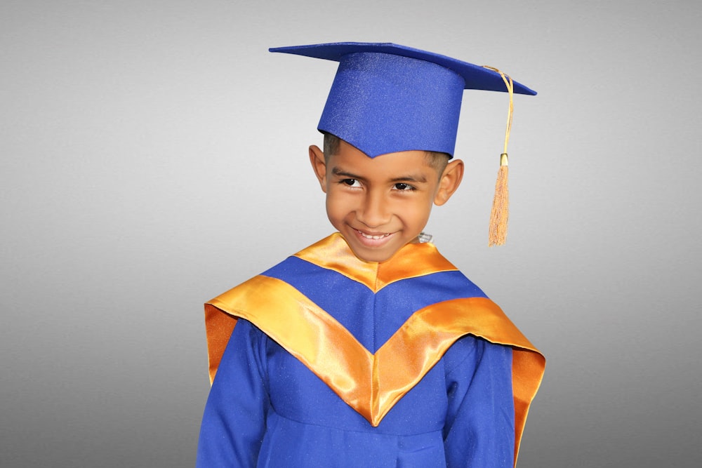 a young boy in a blue graduation gown