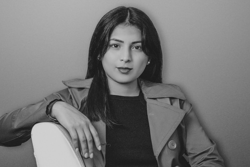 a black and white photo of a woman in a trench coat