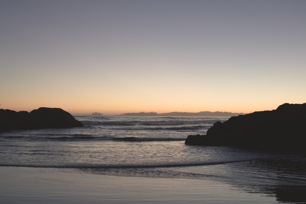 a body of water with rocks in the background