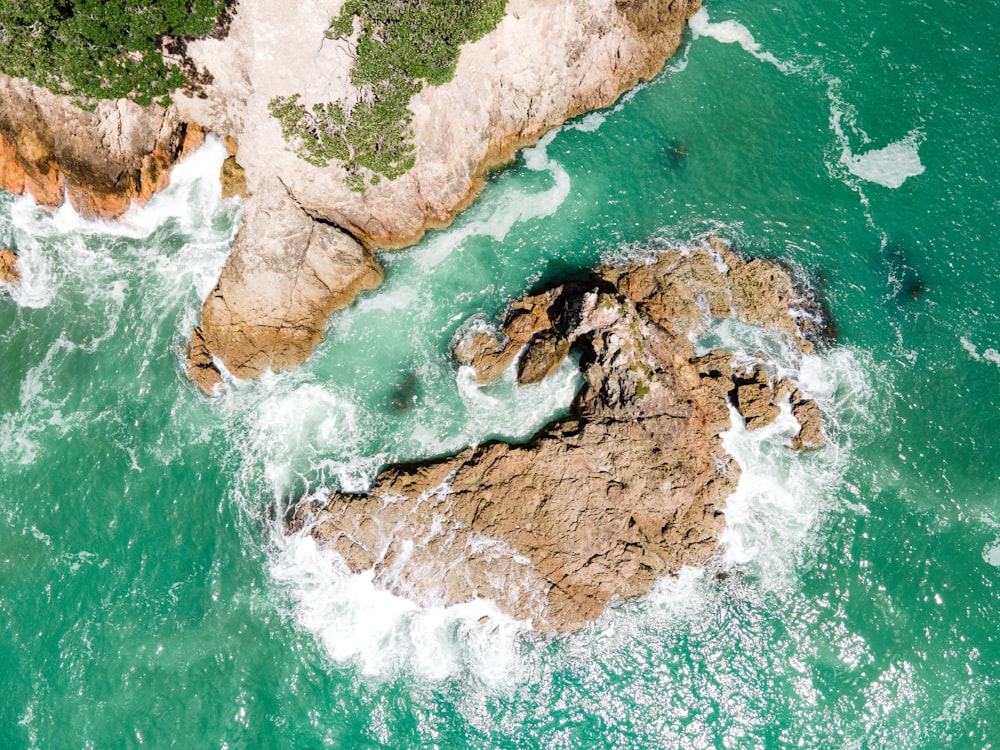 an aerial view of the ocean and rocks