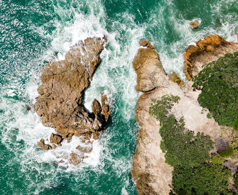 an aerial view of the ocean and rocks