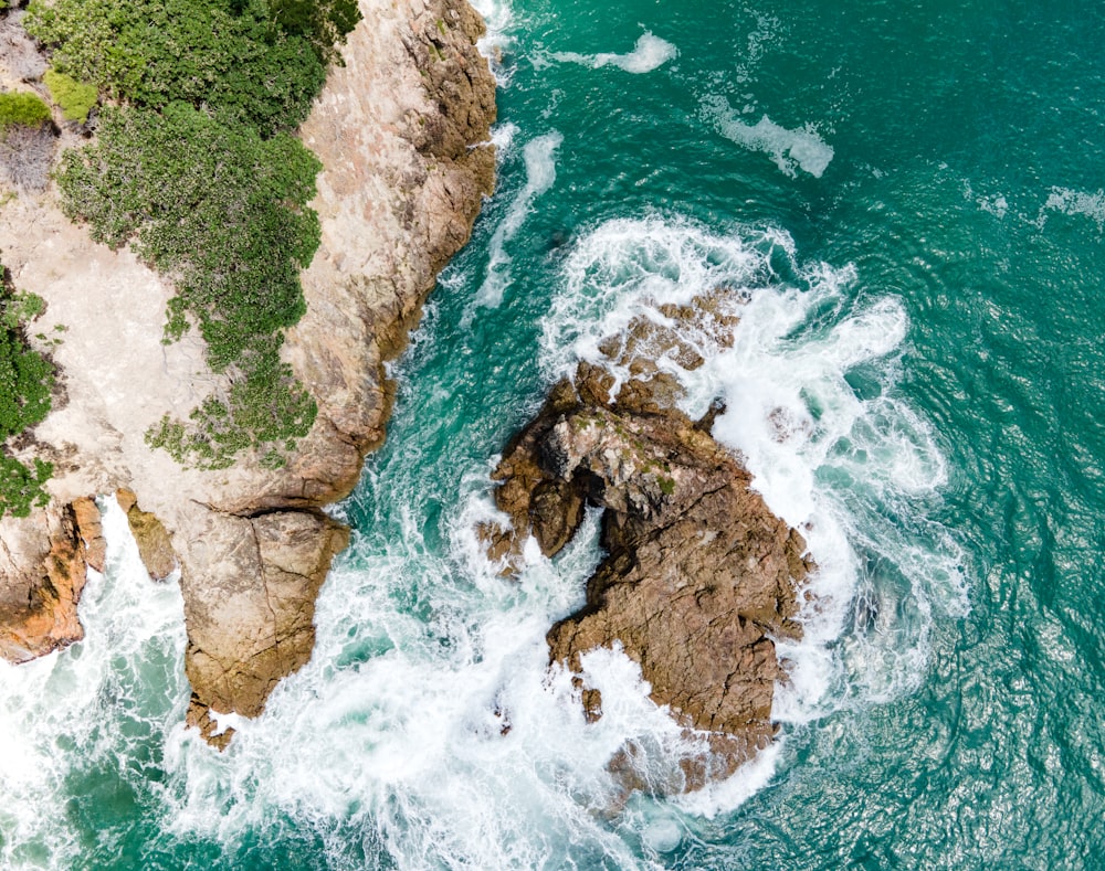 an aerial view of the ocean and rocks