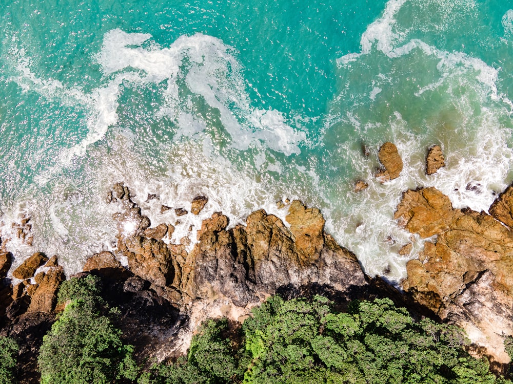 an aerial view of the ocean and rocks