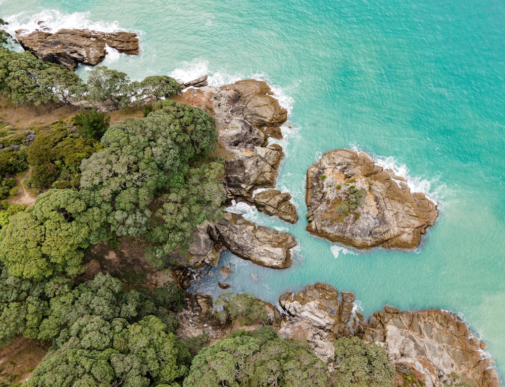 an aerial view of the ocean with rocks and trees