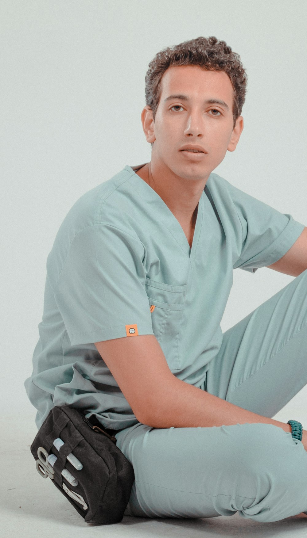 a man in scrubs sitting on the ground