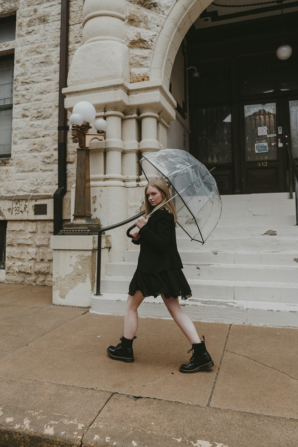 a young girl holding an umbrella while walking down a sidewalk