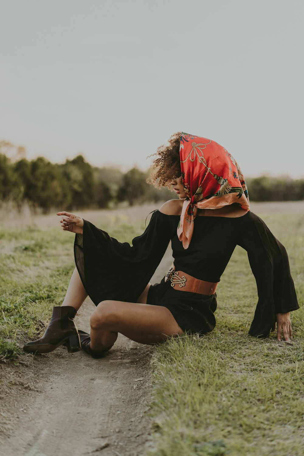 a woman sitting on the ground in a field