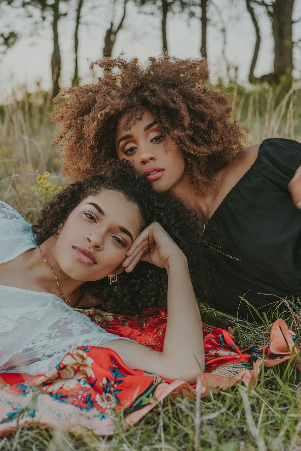 two women laying on a blanket in the grass