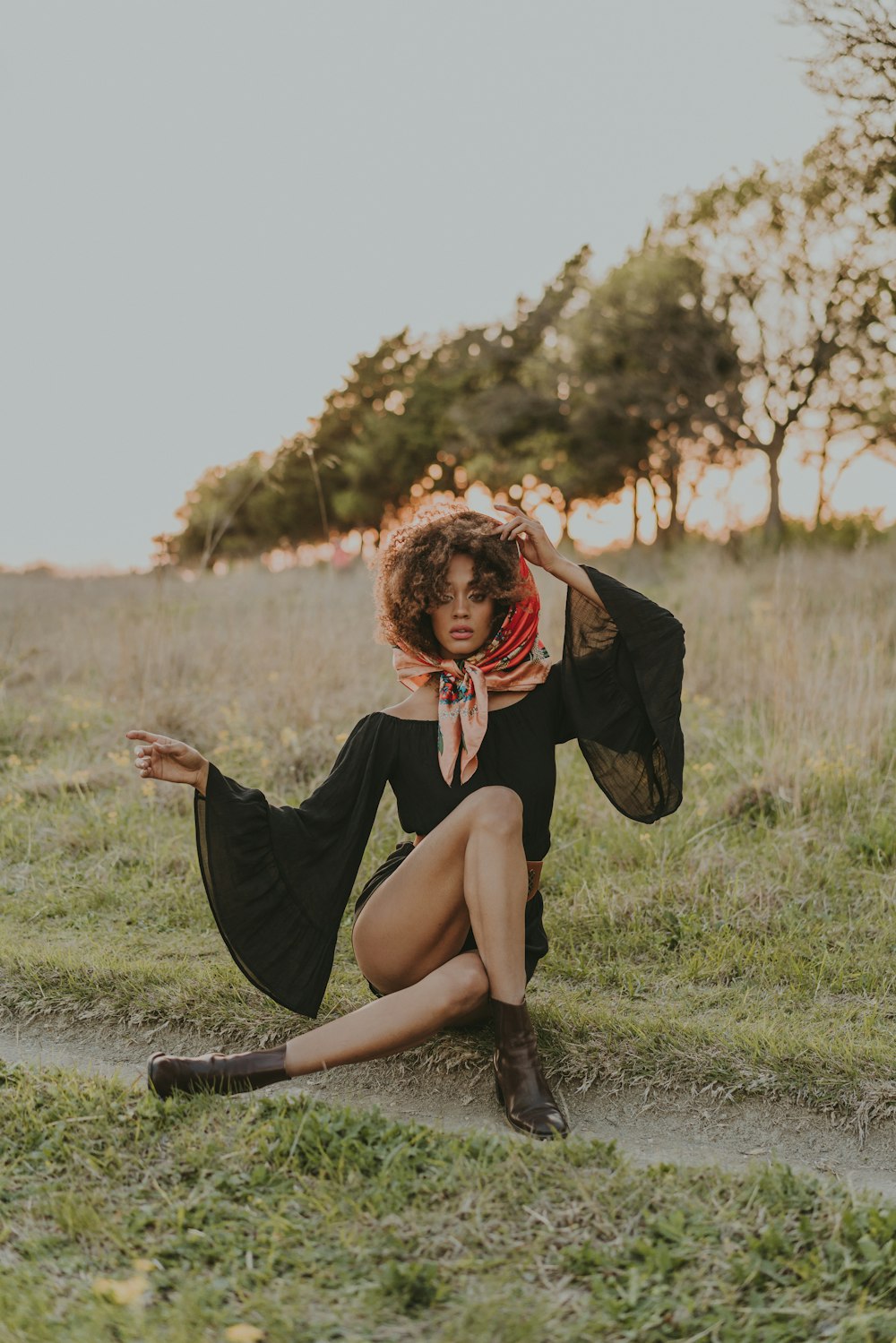 a woman sitting on the ground in a field