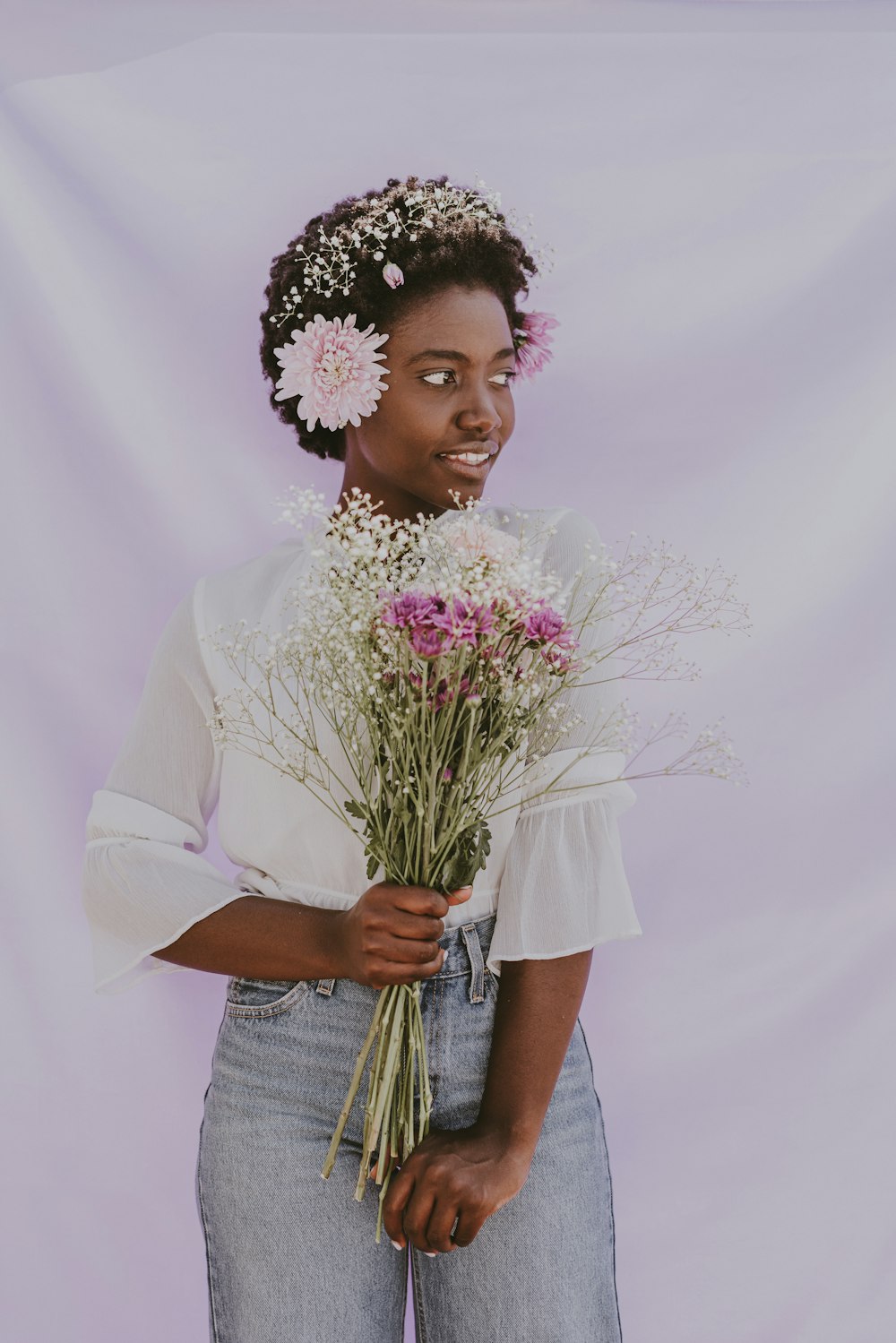 a woman holding a bunch of flowers in her hands