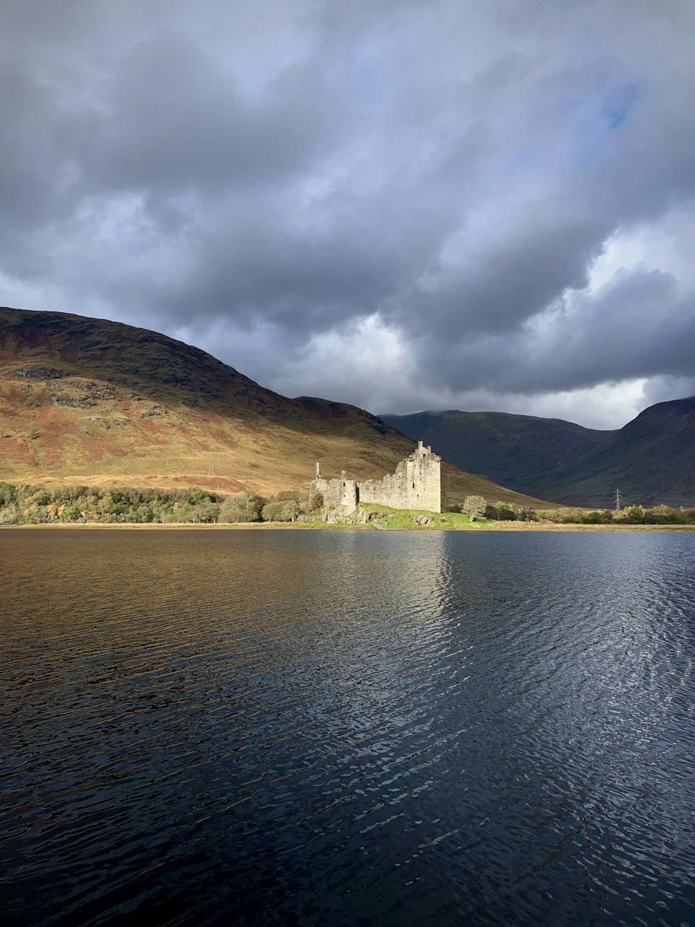 a castle sitting on top of a lake under a cloudy sky