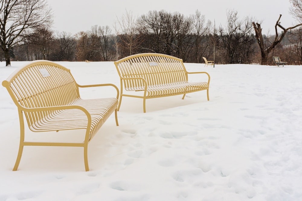 a couple of yellow benches sitting in the snow