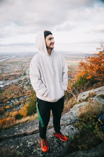 a man in a hoodie standing on top of a mountain