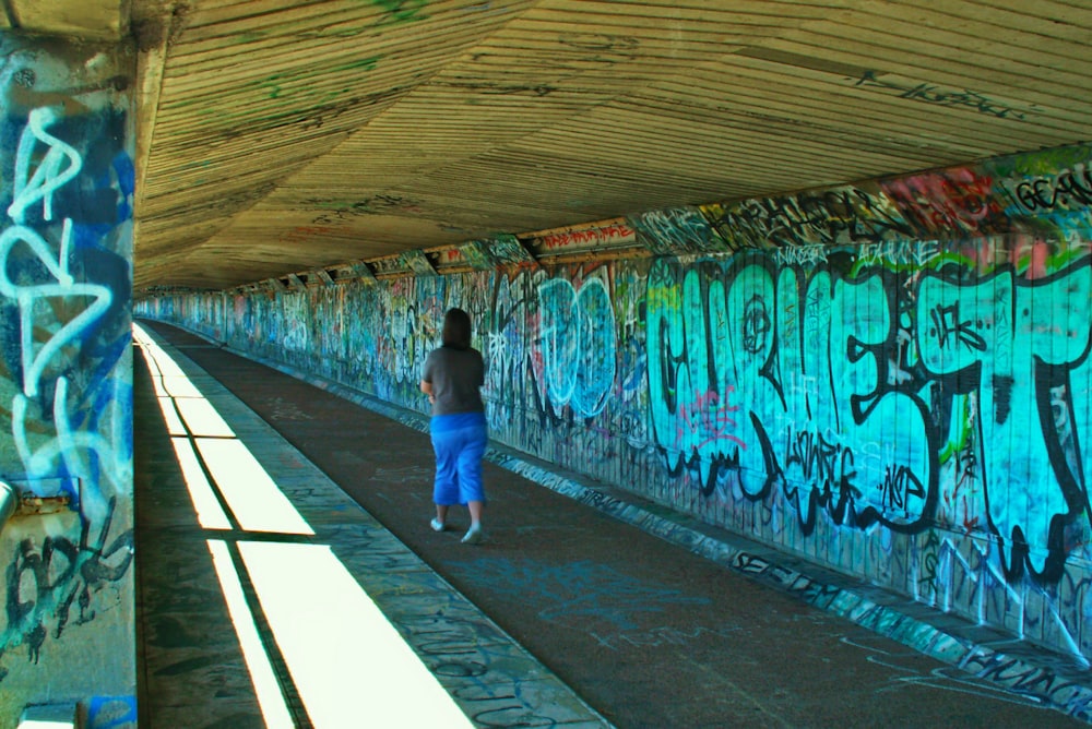 a person walking down a walkway covered in graffiti