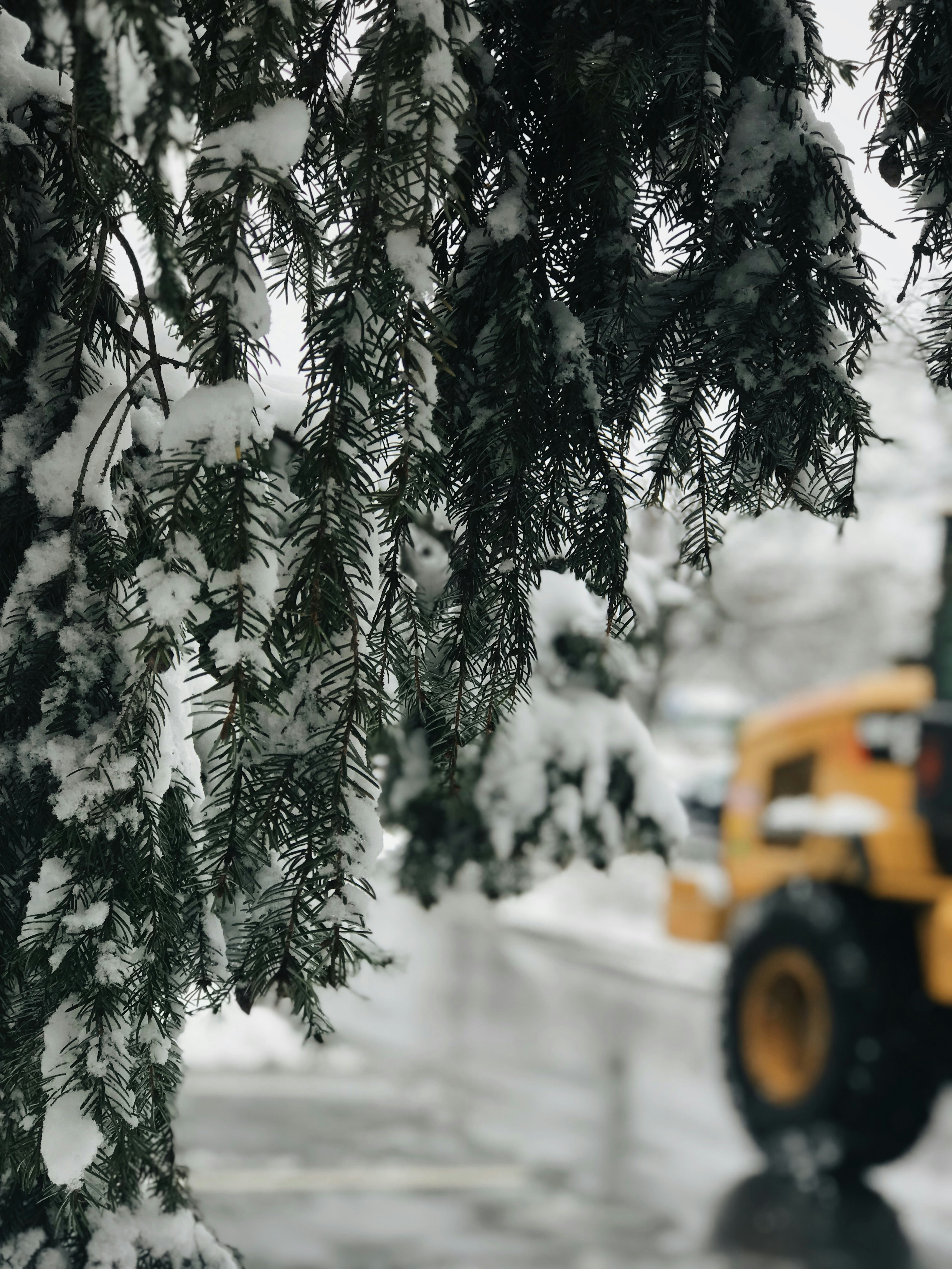 a yellow truck driving down a snow covered road