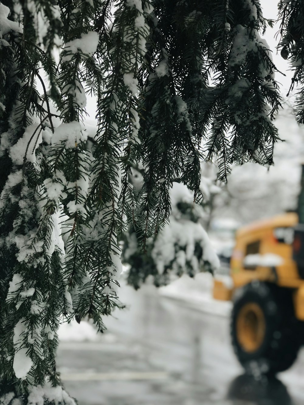 a yellow truck driving down a snow covered road