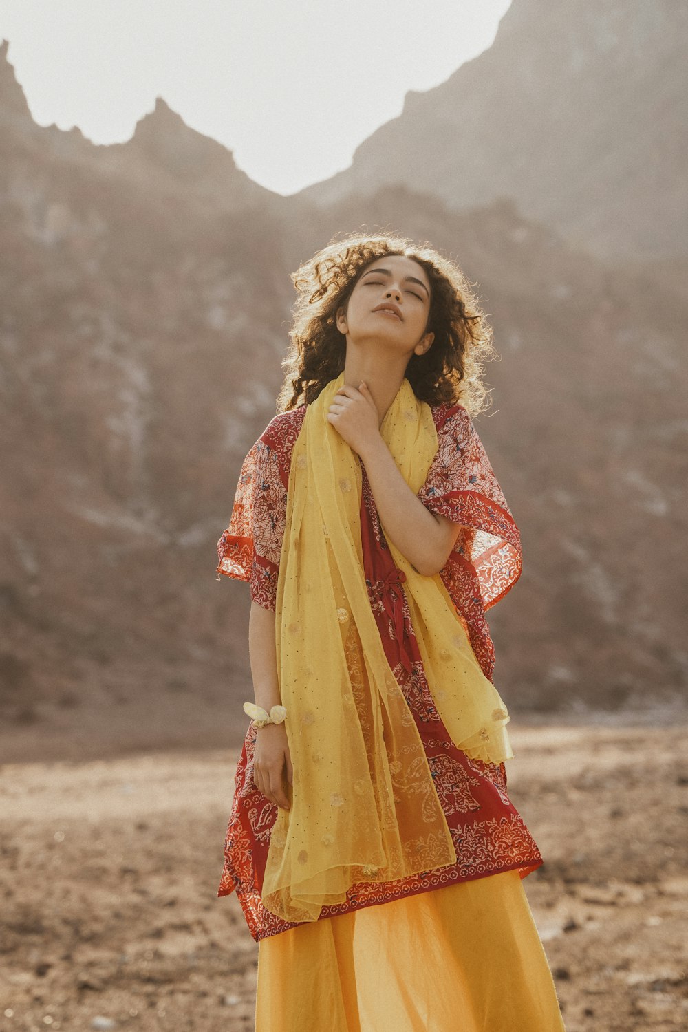 a woman in a yellow dress standing in the desert