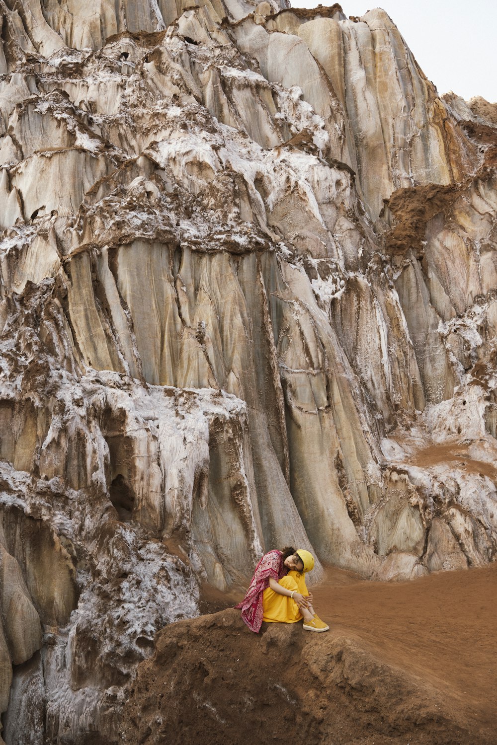 Una mujer sentada en una roca frente a una montaña