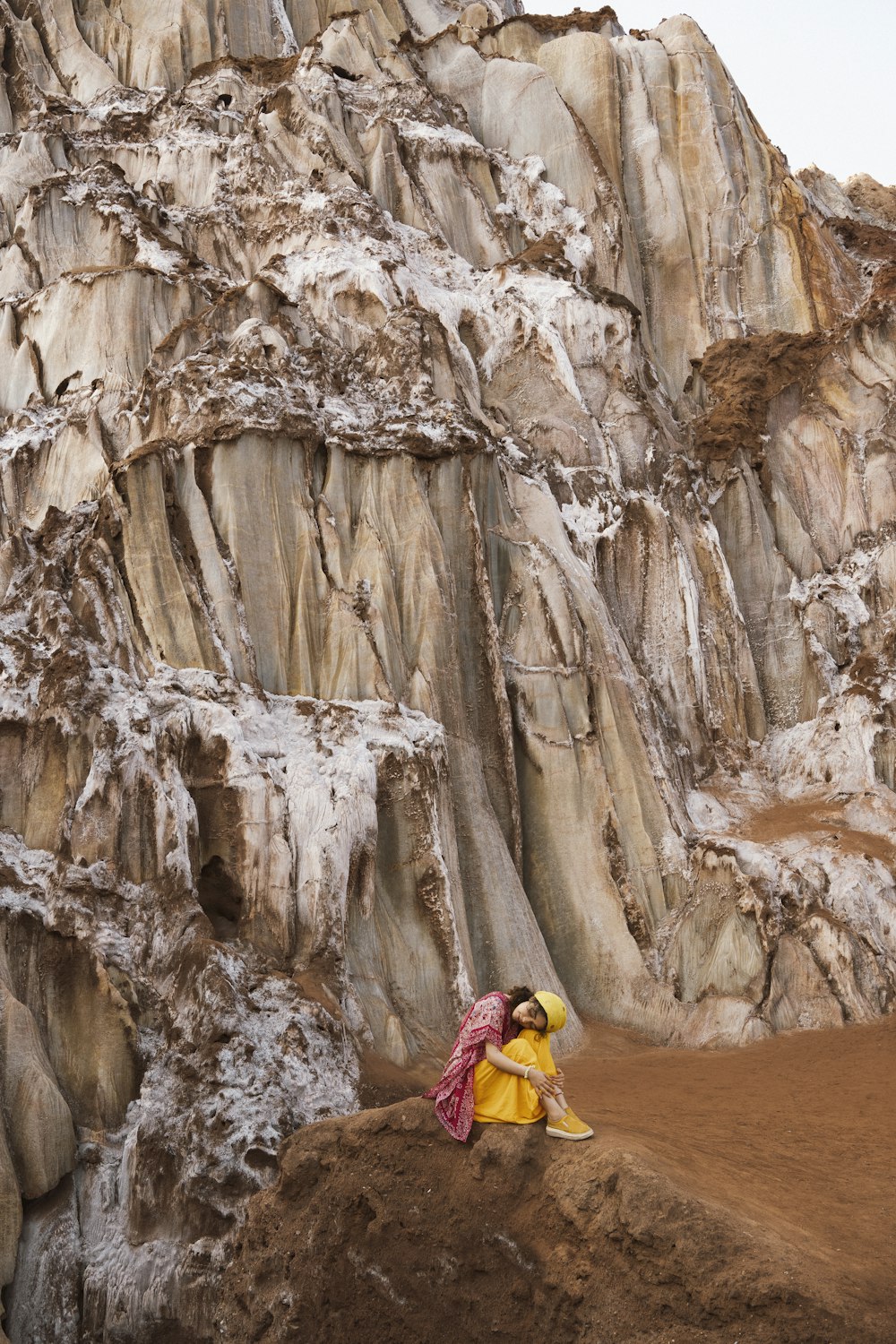 a woman sitting on a rock in front of a mountain