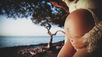 a woman holding a baby in her arms near the ocean