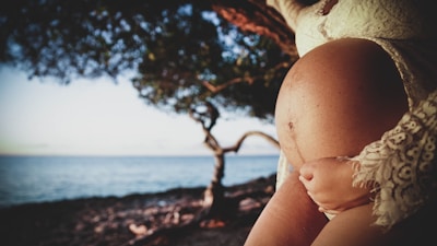 a woman holding a baby in her arms near the ocean