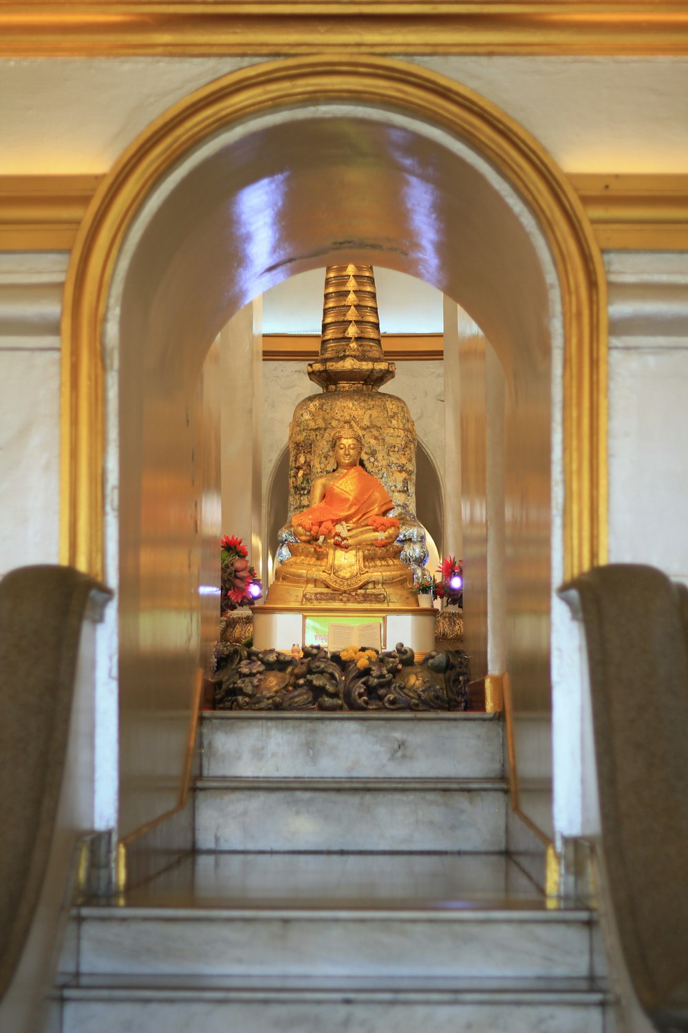 a golden buddha statue sitting on top of a set of stairs