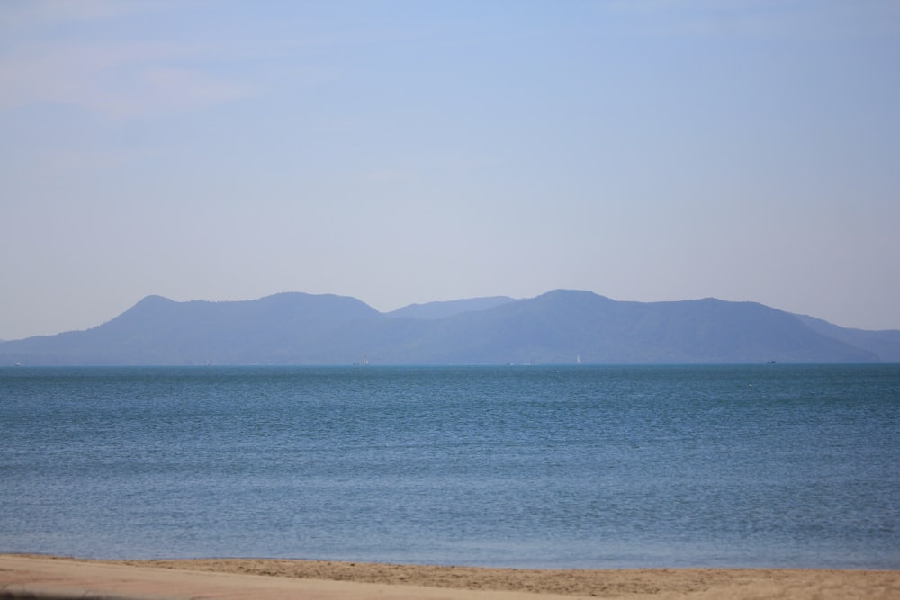 a large body of water with mountains in the background