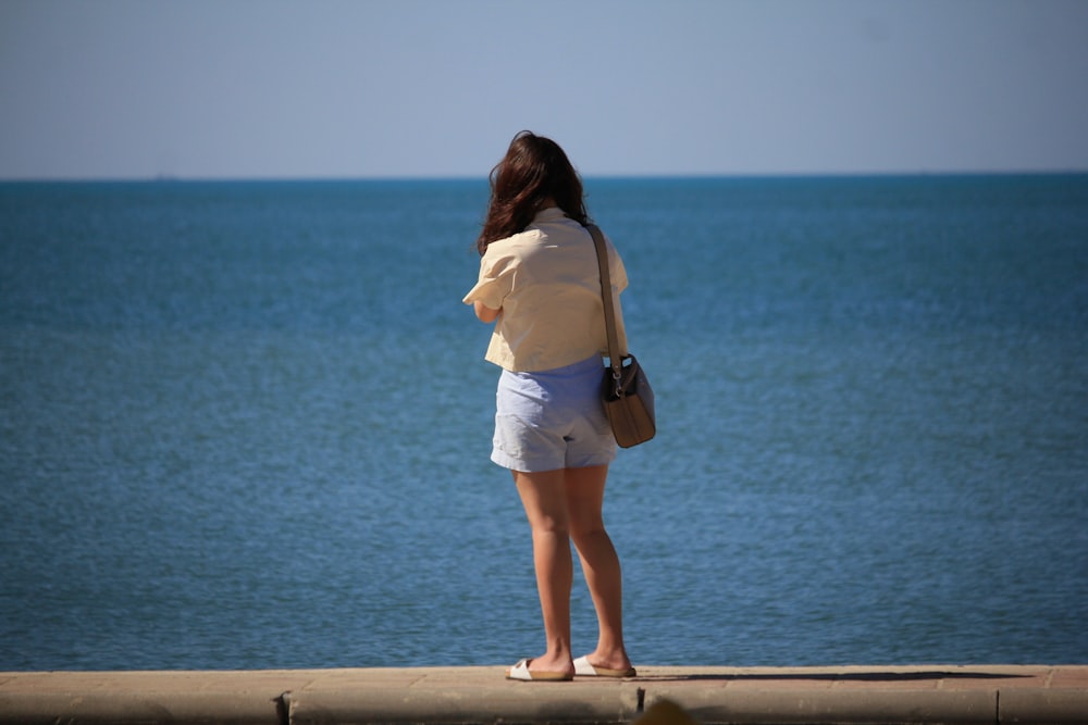a woman standing on a pier looking out at the ocean