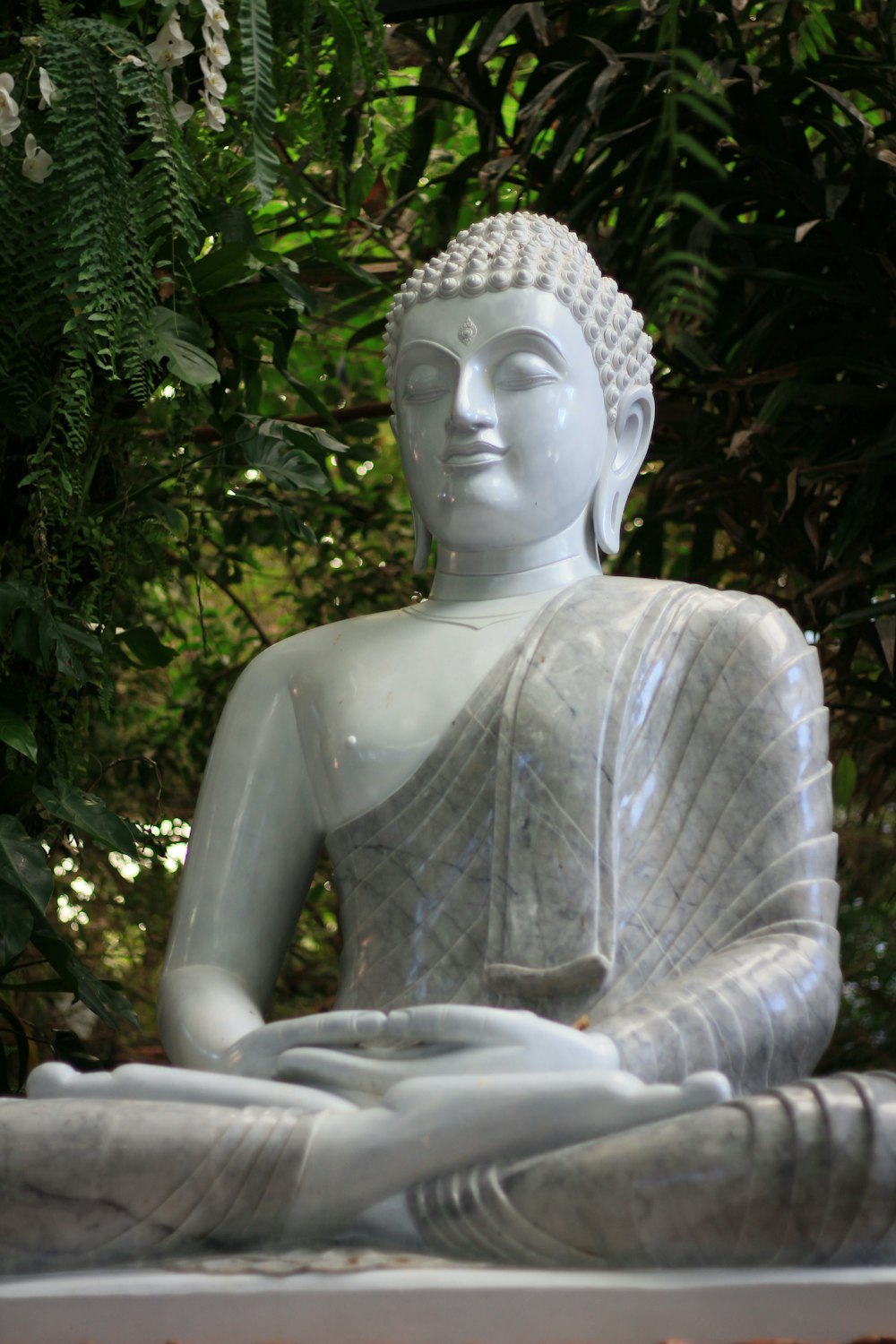 a statue of a buddha sitting in the middle of a forest