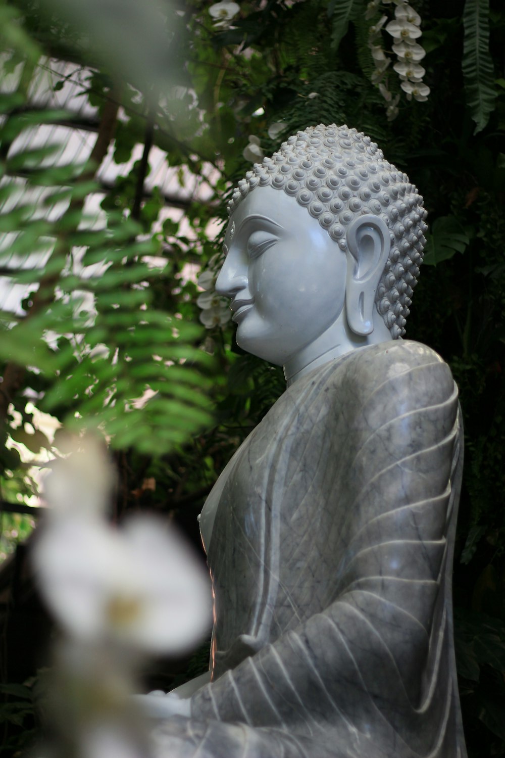 a statue of a buddha sitting in a garden