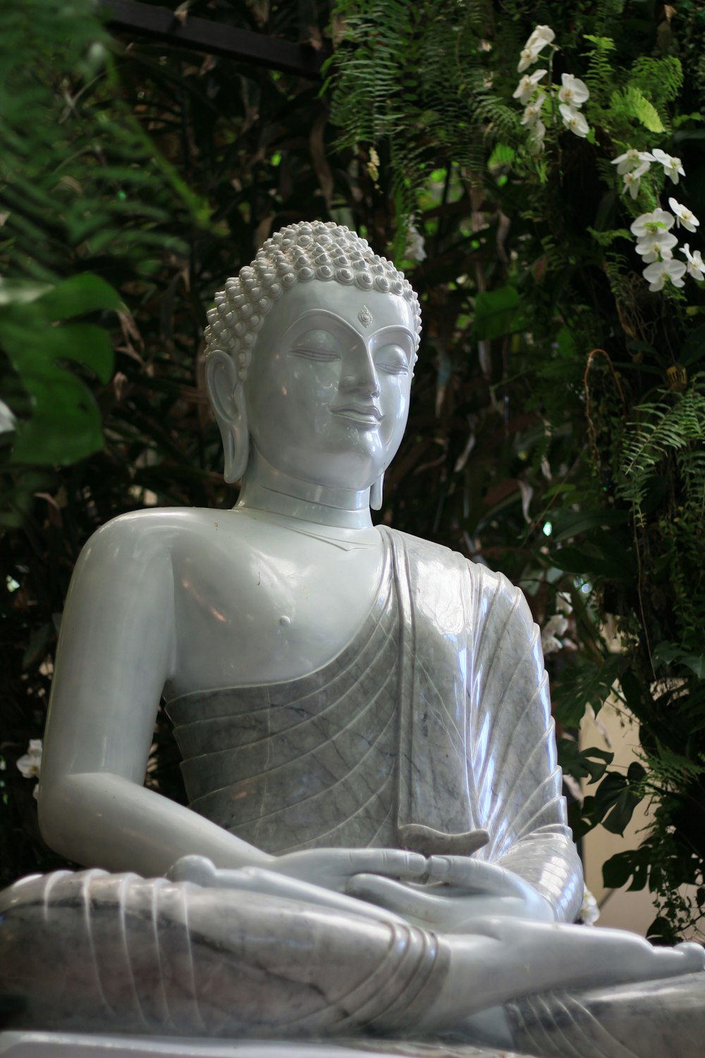 Eine Statue eines Buddha, der in einem Garten sitzt