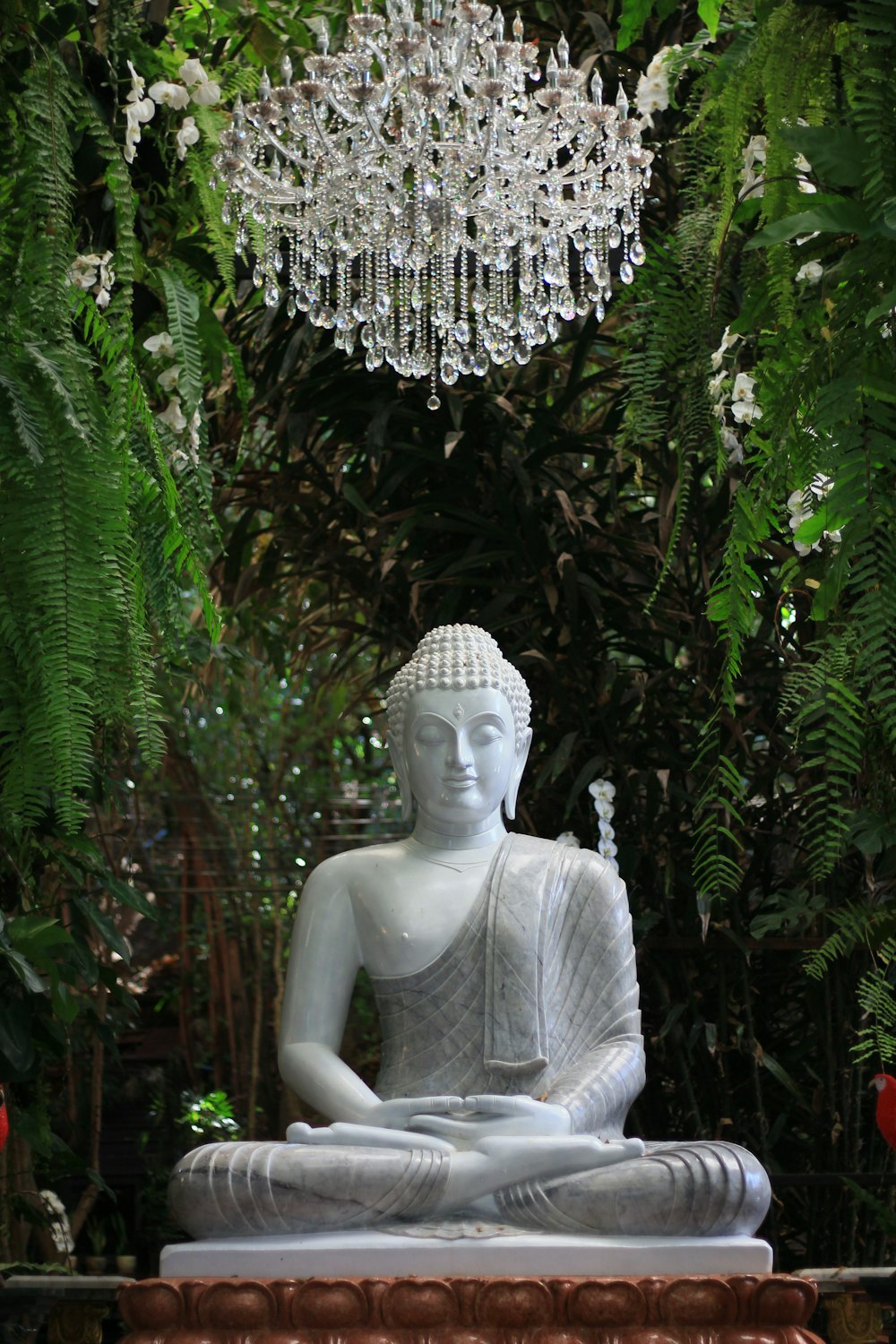 Eine Statue eines Buddha, der in einem Garten sitzt