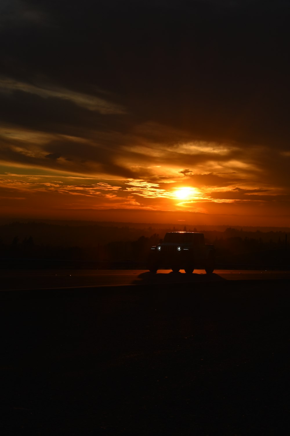 a truck driving down a road at sunset