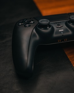 A close-up of a game controller on a sleek black surface.