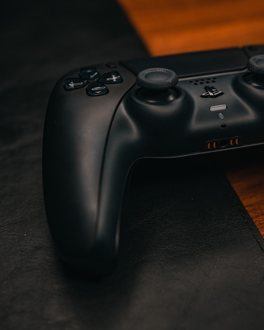 A close-up of a game controller on a sleek black surface.