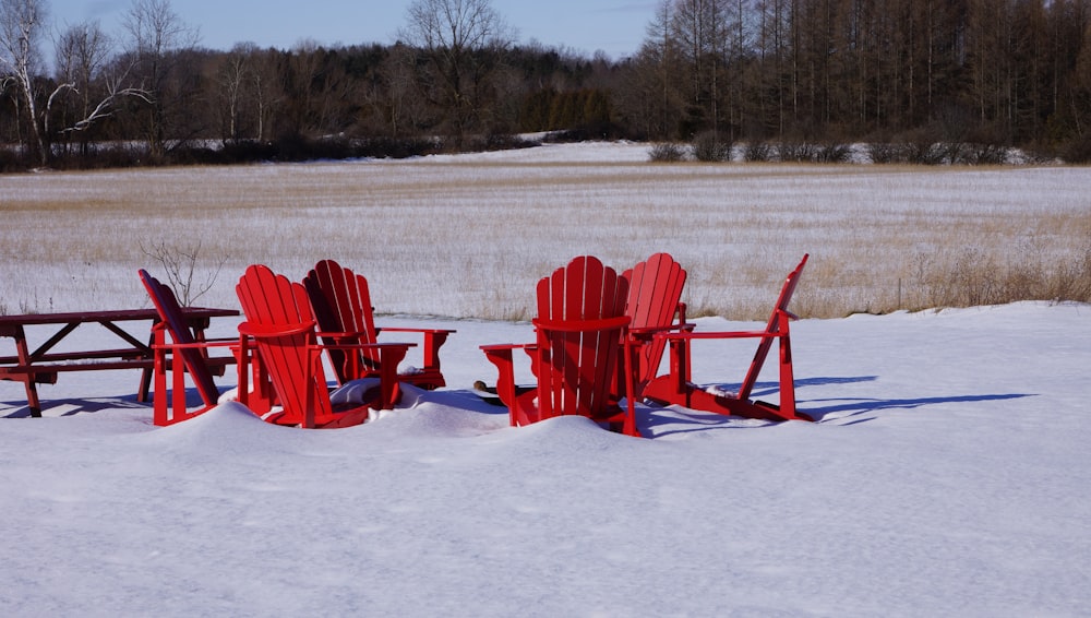 a couple of red chairs sitting on top of a snow covered field
