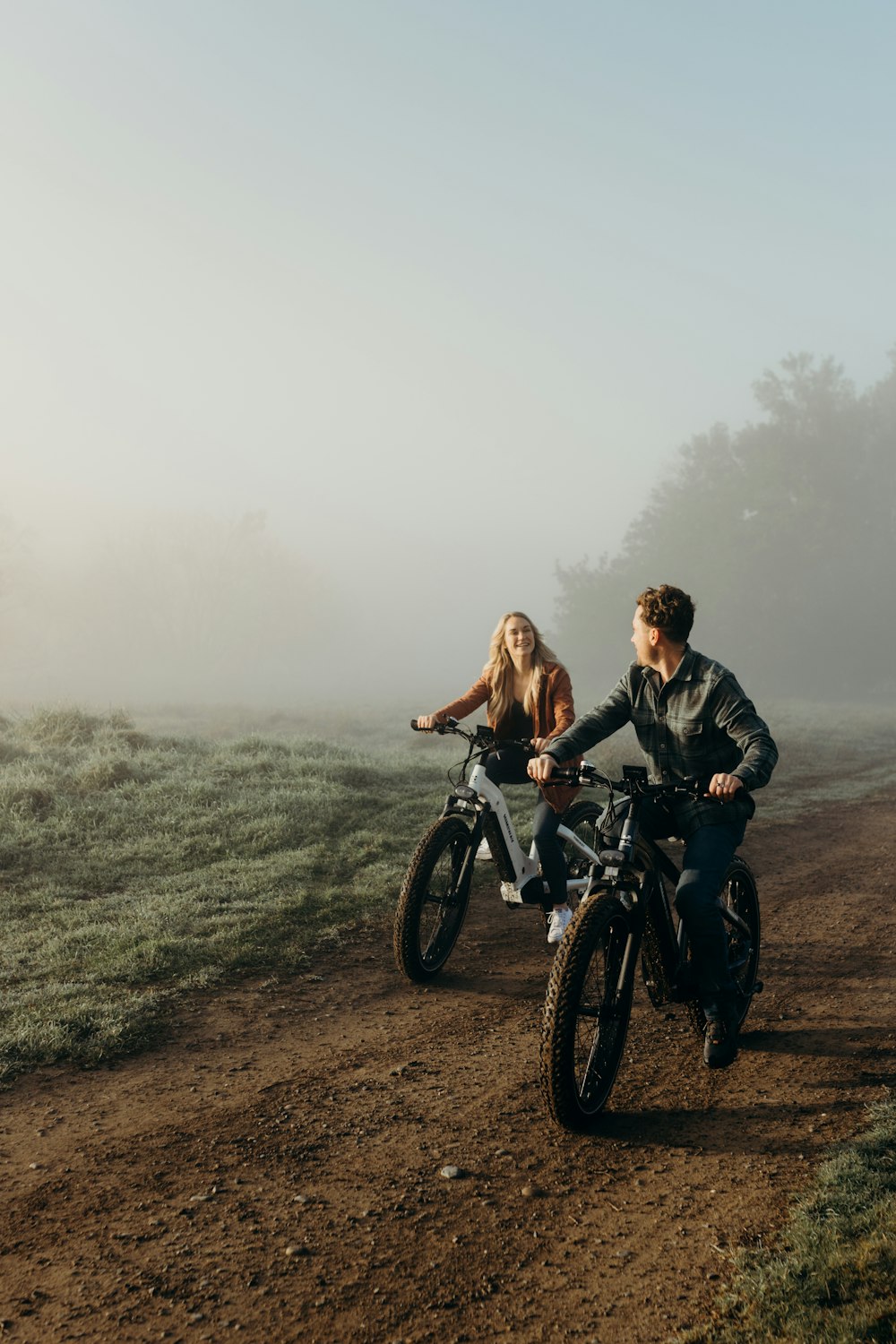 a man and a woman riding a motorcycle down a dirt road