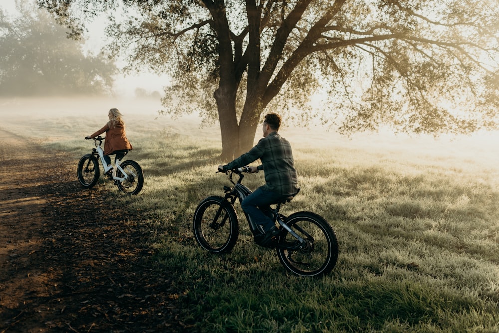 a couple of people riding bikes down a dirt road