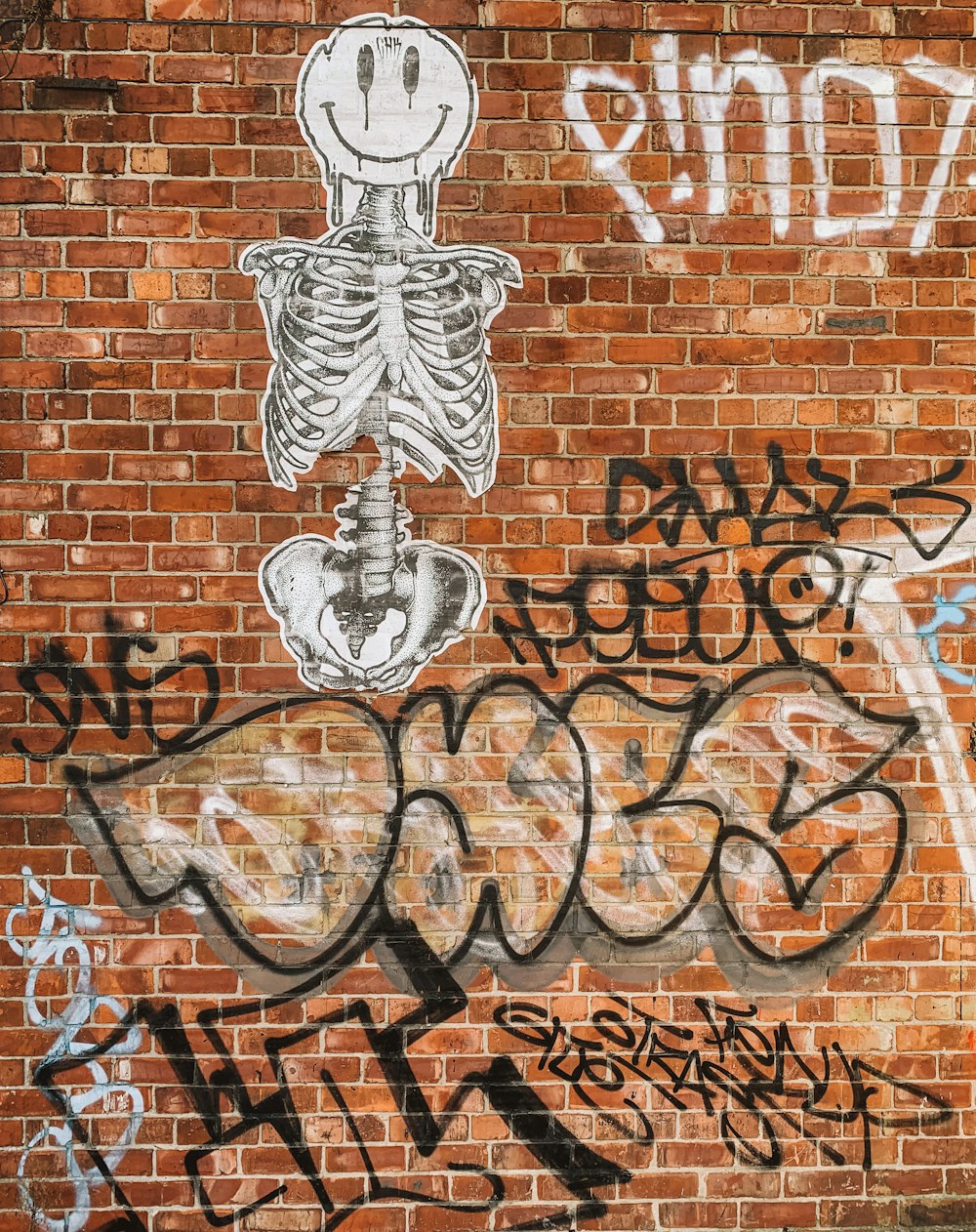 a brick wall with graffiti and a skeleton on it