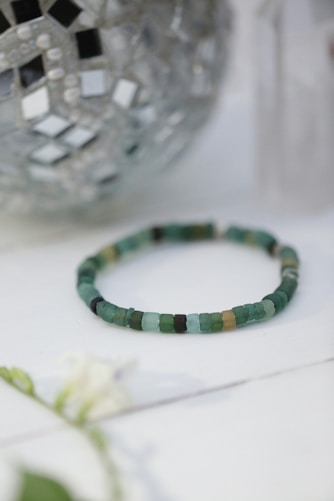 a beaded bracelet sitting on a table next to a vase