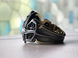 Close-up of a handcrafted copper ring with intricate detailing on a rustic wooden surface.