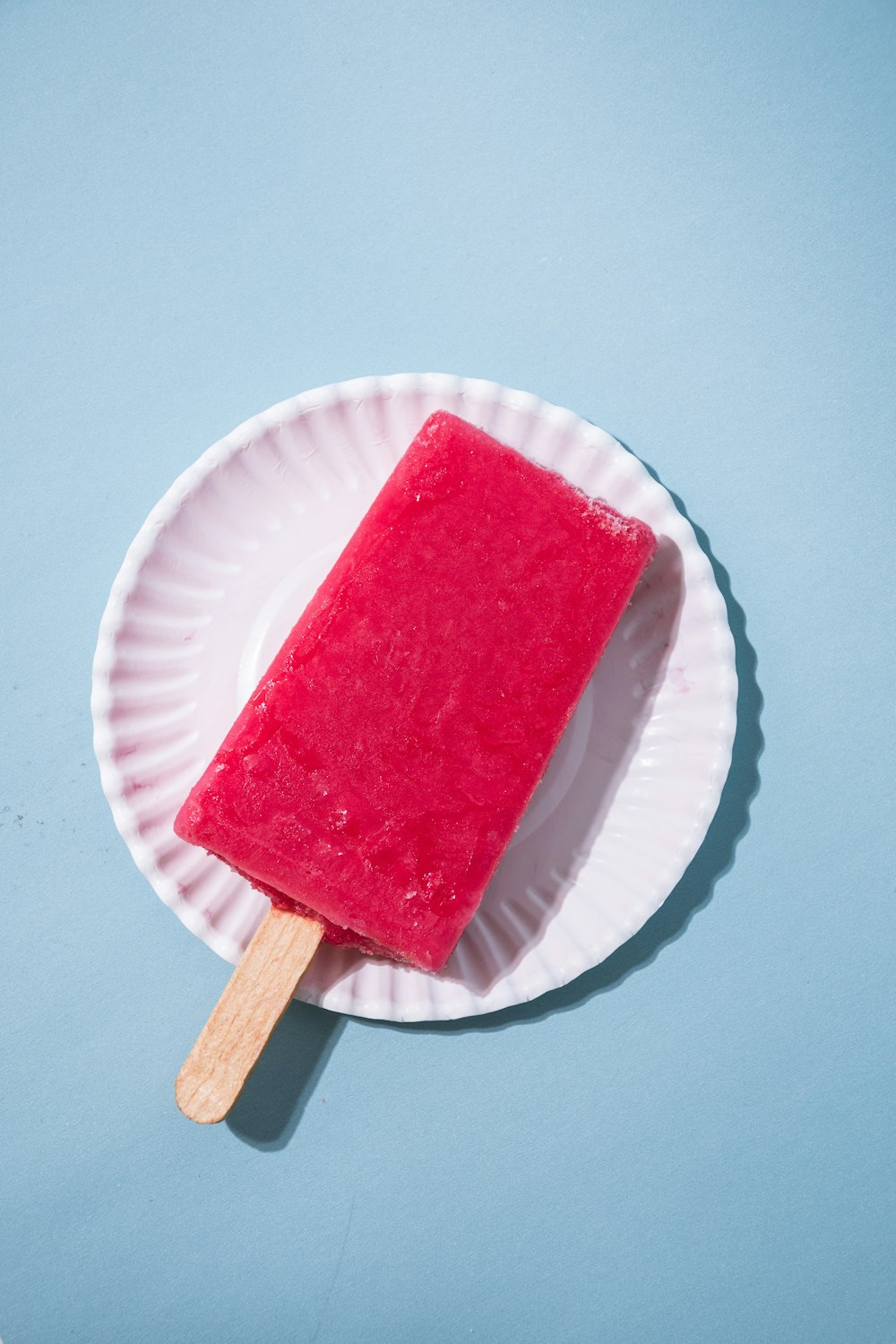 a popsicle on a paper plate on a blue surface