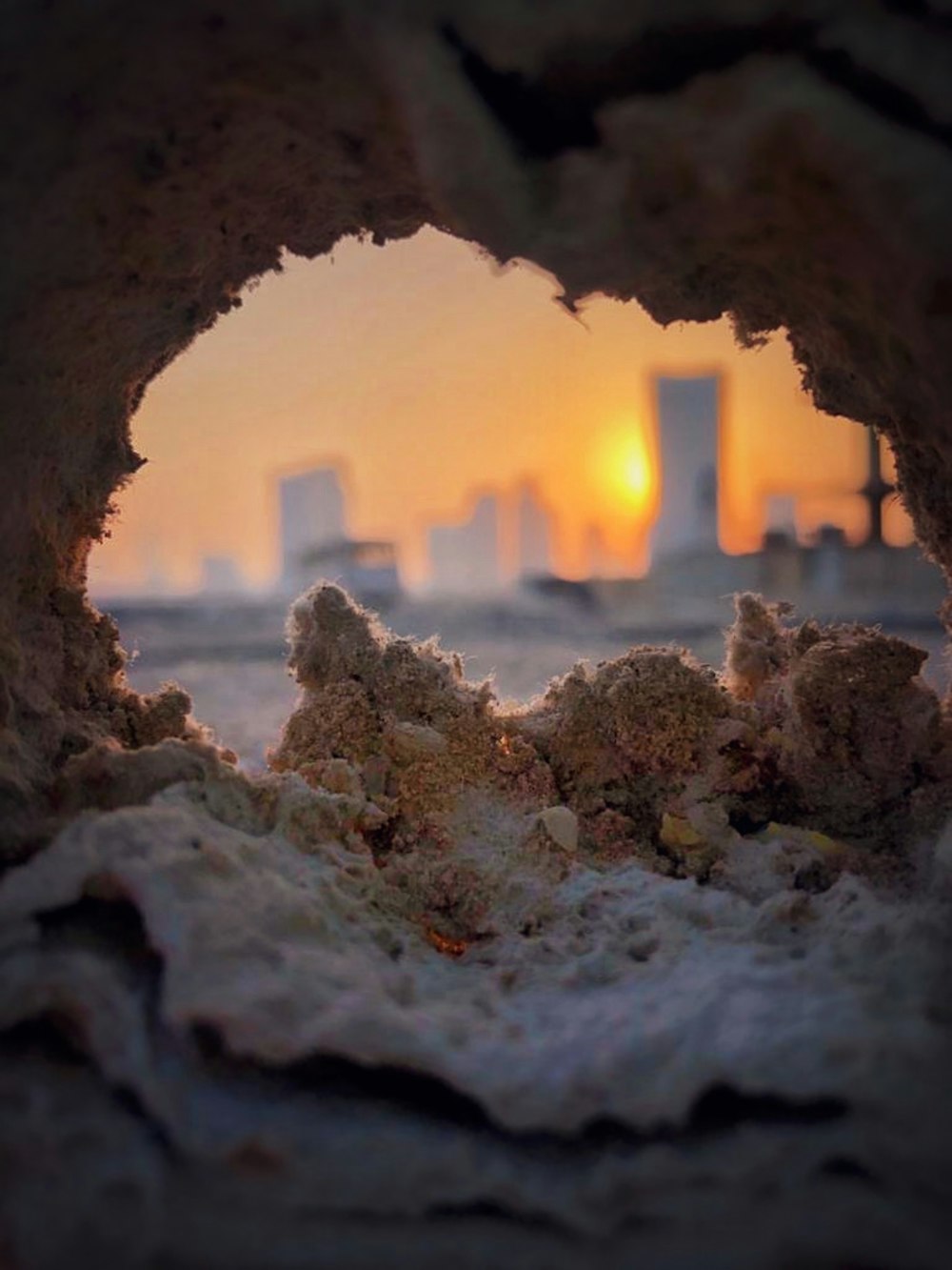 a view of a city through a hole in a rock