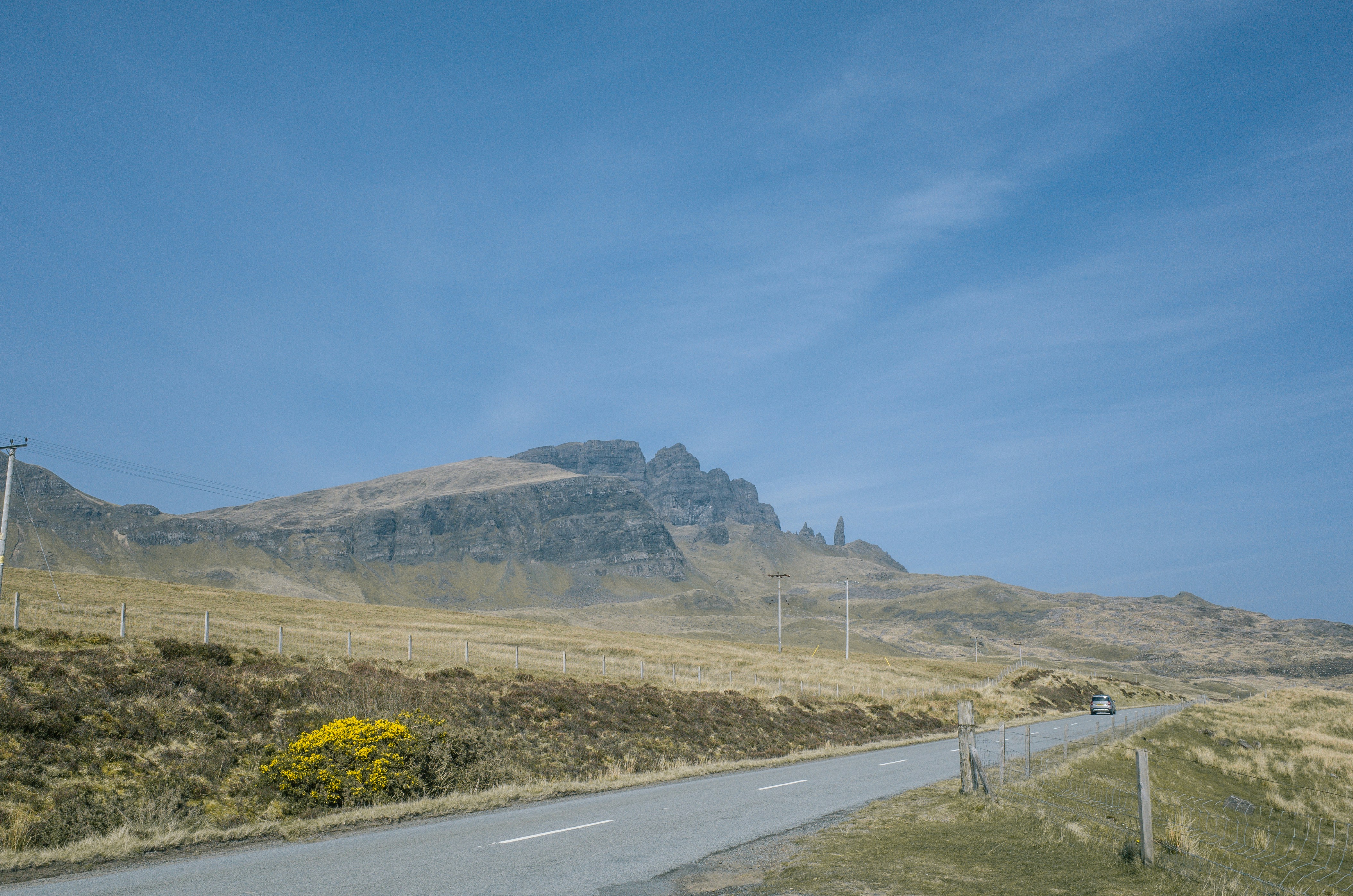 a car driving down a road next to a mountain