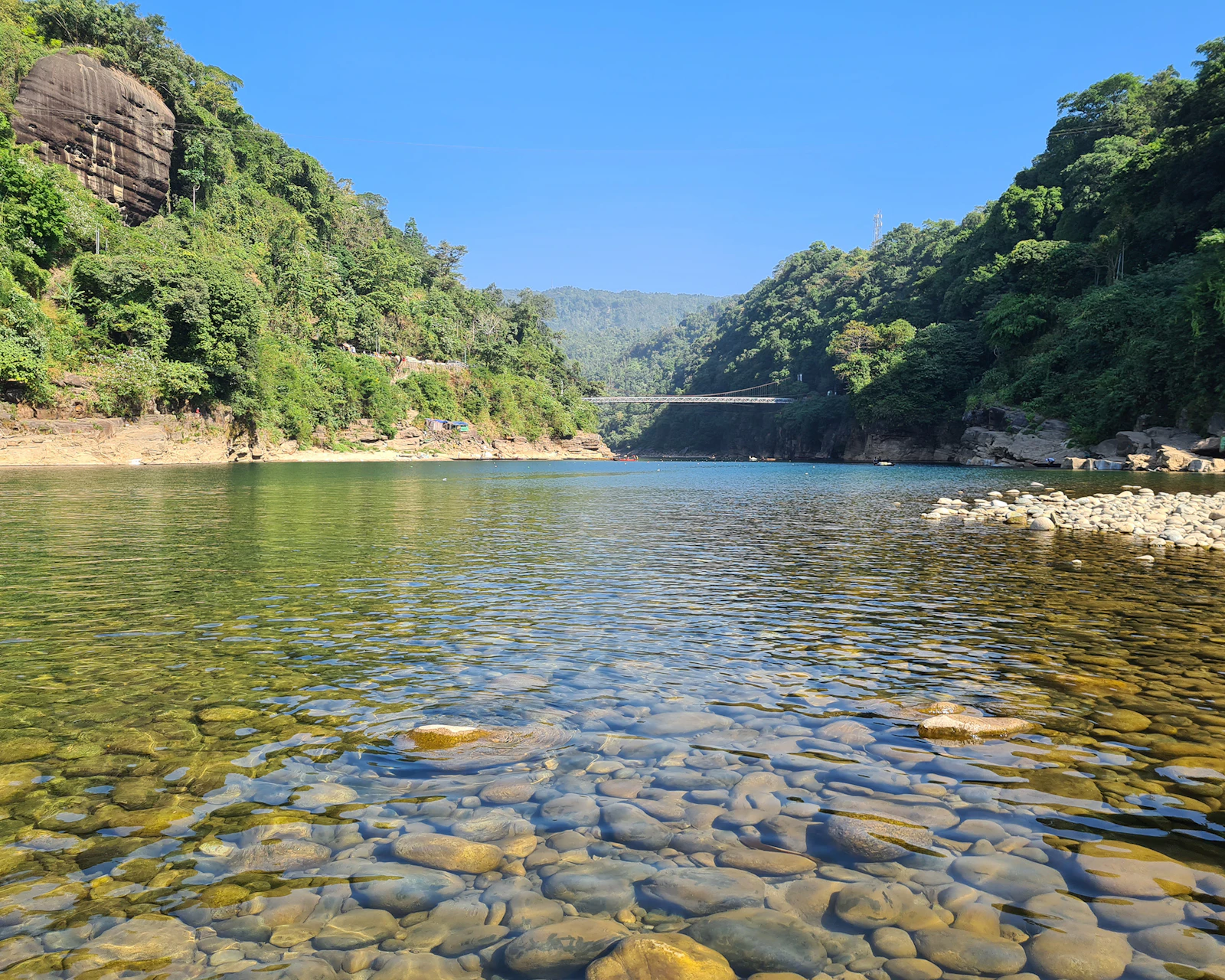 A clear stony river with hills behind