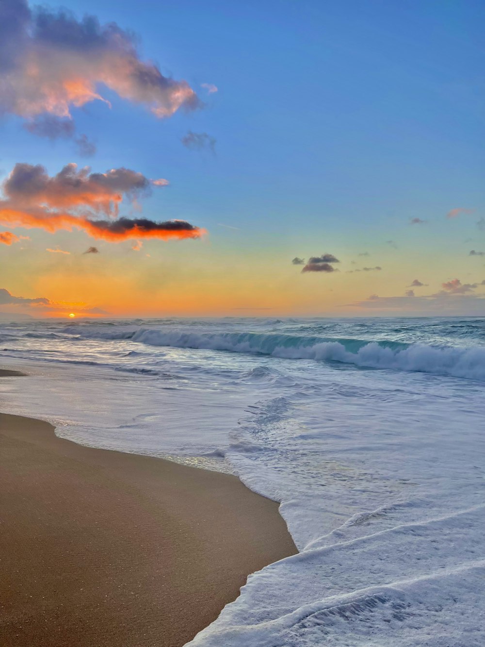 the sun is setting over the ocean on the beach