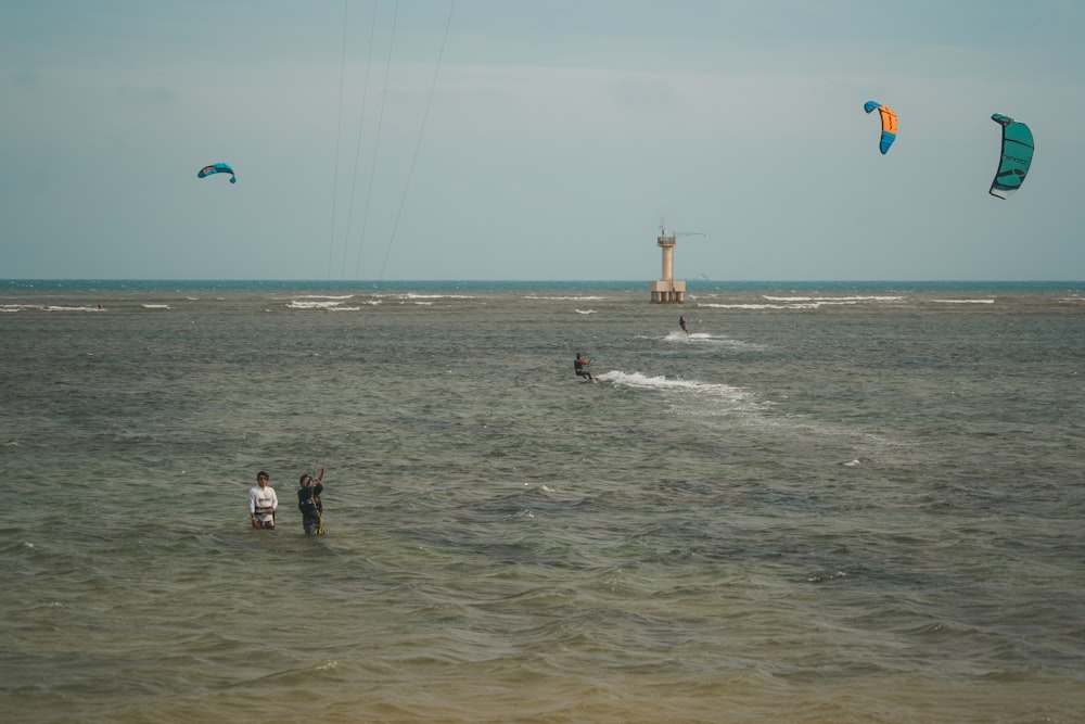 a group of people standing in the ocean flying kites